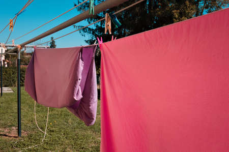 Pink and violet bed sheets hanging on a drying rack in the garden (Pesaro, Italy, Europe)の写真素材