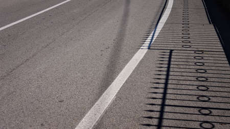 The shadow of a steel fence on the asphalt (Pesaro, Italy, Europe)