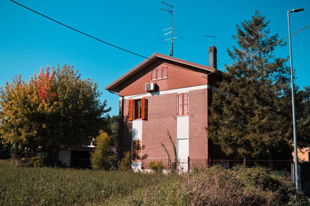 A pink house with an orange opened window and a chimney in the italian countryside (Pesaro, Italy,...