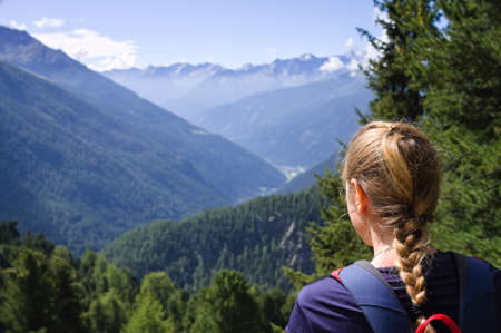 A blonde young girl is watching the panorama in the italian Alps (Trentino, Italy)の写真素材