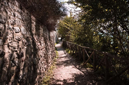 A pathway in the forest along the walls of an italian medieval village (Gubbio, Umbria, Italy, Europe)の写真素材