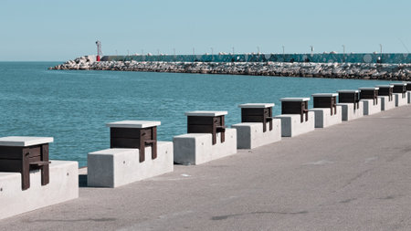 A series of wooden tables with stone benches placed on the edge of the pier of the port of Pesaro (Pesaro, Italy, Europe)の写真素材