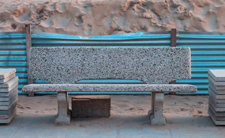 An isolated concrete bench in a construction site on the beach in front of a sand dune (Pesaro,...