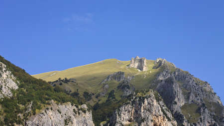 The top of a rocky mountain with green meadows illuminated by a beam of light (Sibillini National Park, Marche, Italy)の写真素材