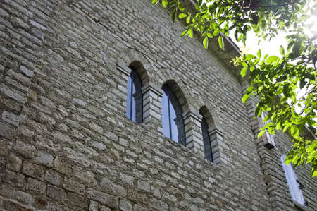 Three gothic stained glass windows in a medieval abbey with sunlight filtering through the treesの写真素材