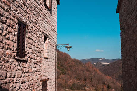 A street lantern hanging on a stone wall with a country landscapeの写真素材