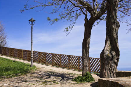 A fenced park with trees and a lamppost overlooking the Mediterranean Seaの写真素材