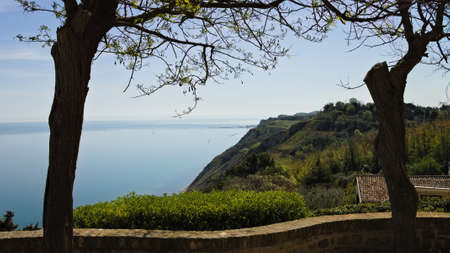 A terrace with plants and trees overlooking the Mediterranean Sea and Monte San Bartolo National Parkの写真素材