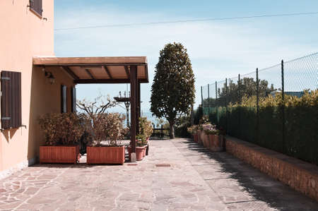 A patio with a wooden gazebo surrounded by plants and flowers (Fiorenzuola di Focara, Marche, Italy)の写真素材