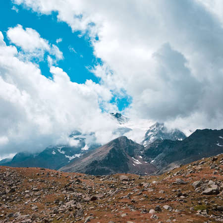 Big clouds above snow capped peaks of mountains in the italian Alps