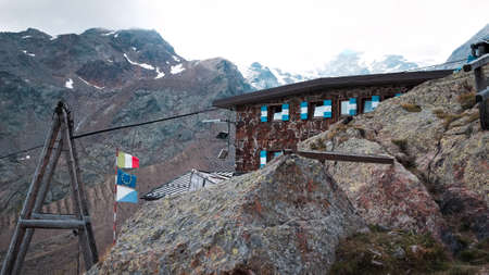 A stone mountain hut in the Italian Alps behind a rock (Trentino, Alps, Italy, Europe)の写真素材