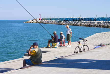 Pesaro, Italy - 9 july 2020: a little boy is fishing with his father and grandfather on the dock of the port of Pesaroのeditorial素材