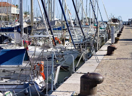 A series of boats moored in the port of Pesaro in front of the mooring bollards on the pier (Marche, Italy, Europe)の写真素材