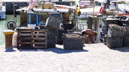 A fisherman is working on his fishing boat at the port of Pesaro with tools of the trade, fishing nets and boxes (Marche, Italy, Europe)のeditorial素材