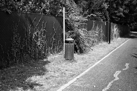 A wooden and metal garbage can on the edge of a pedestrian walkway in a public park (Marche, Italy, Europe)の写真素材