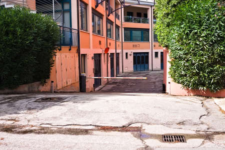 An automatic barrier for access to a basement garage in a pink residential building (Marche, Italy,...