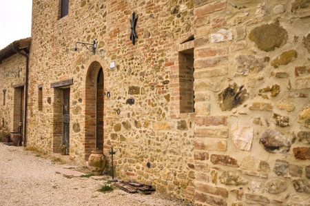 The facade of a rural stone farmhouse with wooden doors and windows in the italian countryside (Tuscany, Italy, Europe)の写真素材