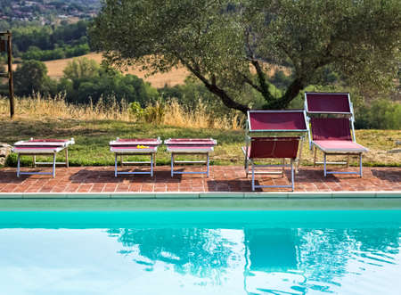 Red sunbeds by the pool in the Italian countryside (Tuscany, Italy, Europe)の写真素材