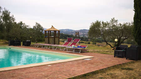 Red sunbeds by the pool in the Italian countryside (Tuscany, Italy, Europe)の写真素材