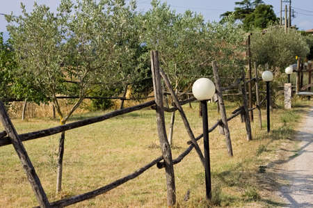 A series of street lamp near a wooden fence in the countryside (Umbria, Italy, Europe)の写真素材
