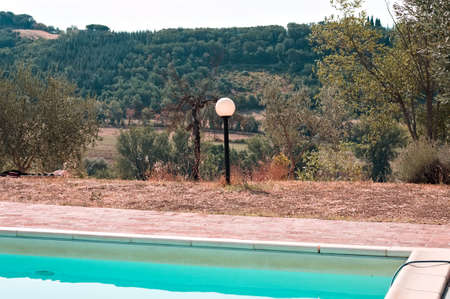 An isolated lamp in the garden near the swimming pool (Umbria, Italy, Europe)の写真素材