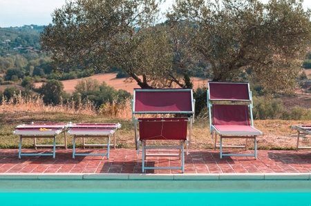 Red sunbeds by the pool in the Italian countryside (Umbria, Italy, Europe)の写真素材