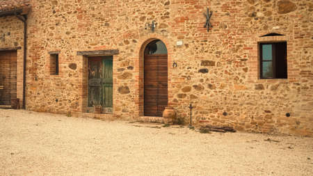 The facade of a rural stone farmhouse with wooden doors and windows in the italian countryside (Tuscany, Italy, Europe)のeditorial素材