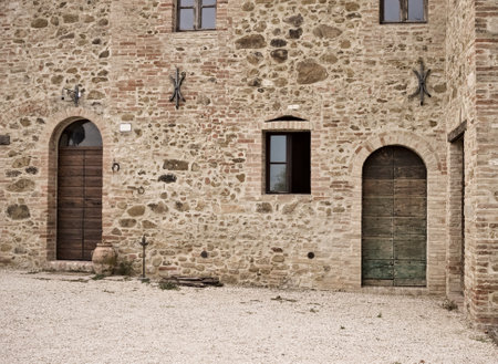 The facade of a rural stone farmhouse with wooden doors and windows in the italian countryside (Tuscany, Italy, Europe)のeditorial素材