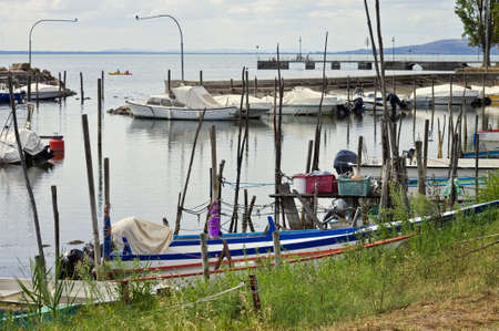 Small motor boats moored on wooden poles of the pier of a small port in Lake Trasimeno (Umbria, Italy, Europe)の写真素材