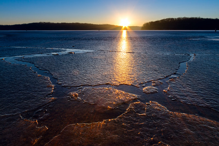 Sunset over an ice covered lake with the ice glowing from the sunraysの写真素材