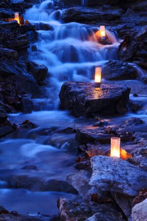 A cascading waterfall with candles during the twilight hours.の写真素材