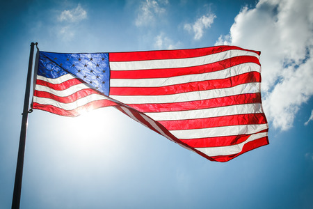 United States of America Flag with clouds and the sun shining through itの写真素材