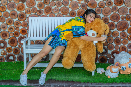 the girl enjoy  hugging Brown big bear and very happy and drink coffeeの写真素材