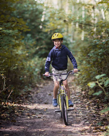 Boy riding a bike in the forest on a sunny autumn day.の写真素材