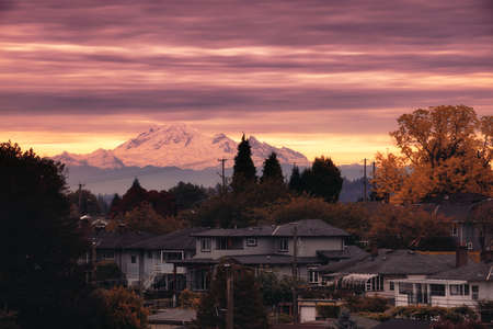 A vertical shot of a mountain surrounded by houses under a cloudy skyの写真素材