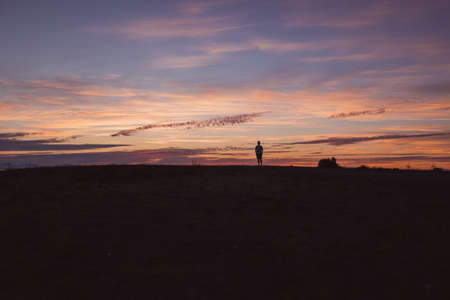 Silhouette of a man on top of a hill at sunsetの写真素材