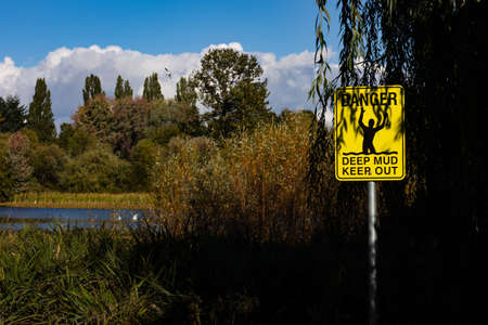 Warning sign on the bank of a lake in the autumn season.の写真素材