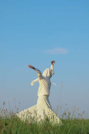 A young woman dancing grass fields with the beautiful blue sky background.の写真素材