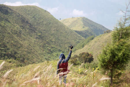 The young man standing on top of the mountain and lifted the camera. Location, Mt. Prau, Indonesiaの写真素材