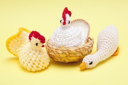 Easter decorations - hand made yarn two chickens and goose on a yellow backgroundの写真素材