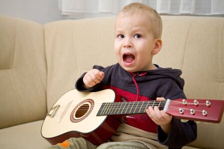 Boy singing and playing the guitarの写真素材