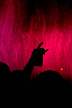 Fountains illuminated red light with silhouette of human hand in the foregroundの写真素材