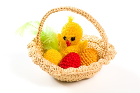 Easter decorations - yarn basket with chicken, eggs and feather on white backgroundの写真素材
