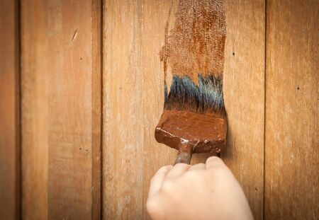 hand with a paint brush painting wooden wallの写真素材