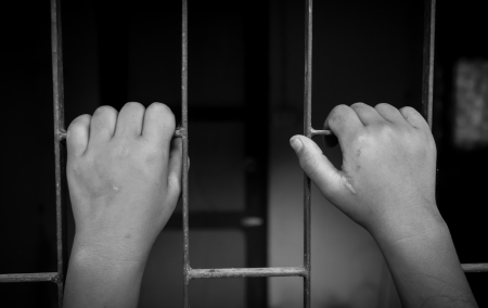 hands of a girl are grabbing steel cageの写真素材