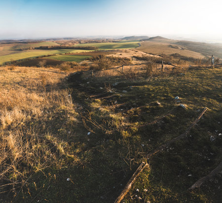 Autumn landscape, view from a hill top to the wide brown land with green field and path in the front.の写真素材