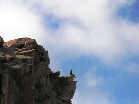 Man sitting on a rocky ledge nears the summit of Pikes Peak.の写真素材