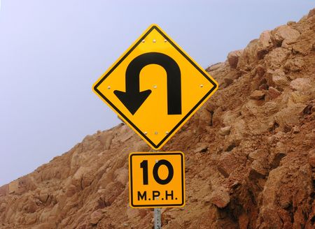 Mountain road sign warning of sharp turn ahead.