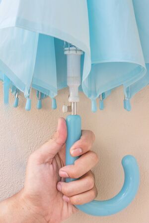 The blue umbrella in hand on the white backgroundの写真素材