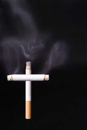 Cigarette cross against a black background の写真素材